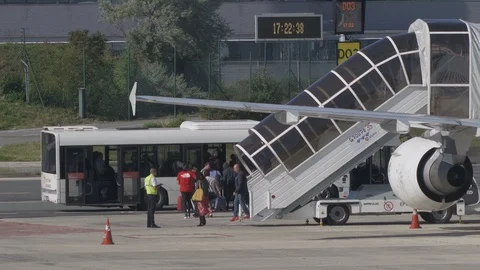 Passengers disembark plane using boarding stairs then board airport bus v3 Stock Footage 119830899