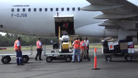 Passengers disembarking, technicians unloading suitcases from a plane Stock Footage 297202377
