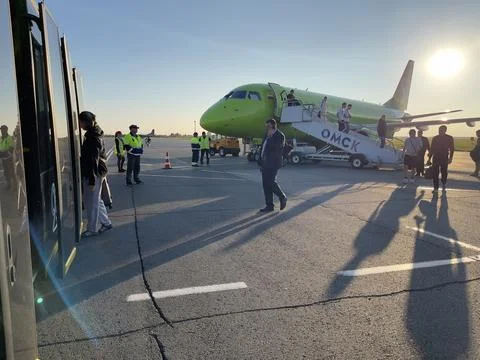 Passengers get off the plane and board a bus. Stock Photos