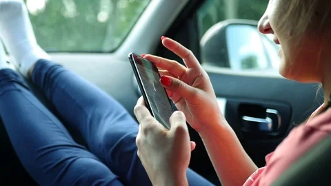 The passenger's girl is riding in the front seat of the car, writes a message on Stock Footage