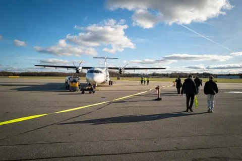 Passengers go to the white propeller plane of Luebeck Air at Luebeck Airport Stock Photos
