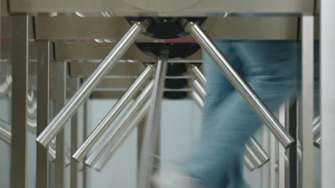 Passengers going through steel tripod turnstile gate security tourniquet subway Stock Footage 275085372