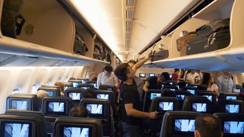 Passengers Inside the Plane Look for Seats, Put Away Things on Shelves Stock Footage 122989995