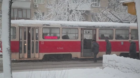 Passengers leave and go to the tram at a stop in winter Stock Footage 83785407