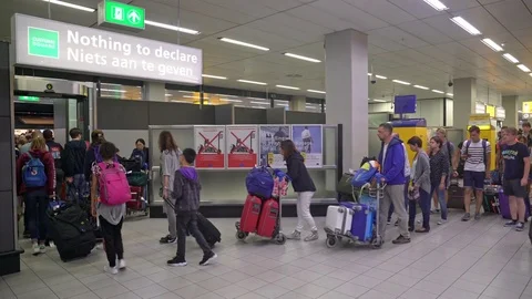 Passengers leaving baggage hall through nothing to declare Schiphol Airport Stock Footage 72463370