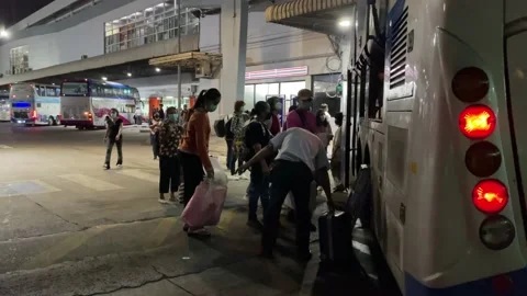 Passengers loading backpack on double decker bus at Bangkok bus terminal night Stock Footage 189434593