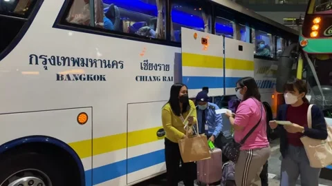 Passengers loading backpack on double decker bus at Bangkok bus terminal night Stock Footage 189442627