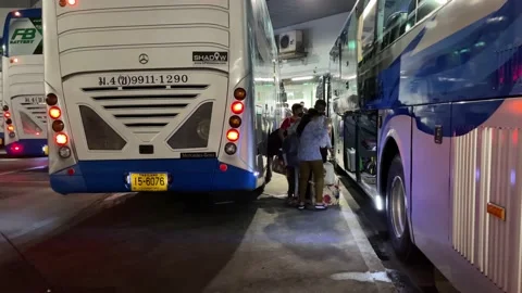 Passengers loading backpack on double decker bus at Bangkok bus terminal night 库存影片 189460251