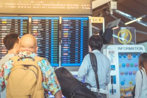 Passengers looking at the flight information board and checking their flight  Stock Photos