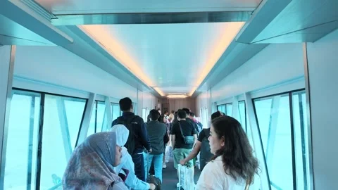 Passengers queue to board a commercial airplane through a jet bridge at an Video stock 342906480