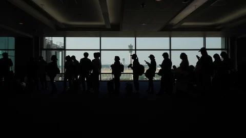 Passengers queue at boarding gate, silhouettes against terminal window Stock Footage 126939705