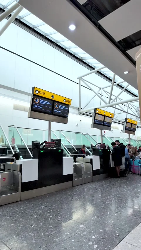 Passengers queue at Heathrow Terminal 4 check-in counters dropping luggage and Stock Footage 334973471