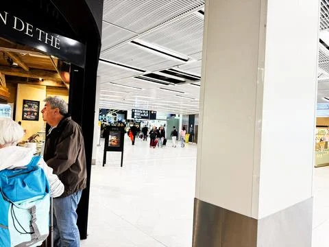 Passengers queuing at a cafe and walking through a bright airport terminal .. Stock Photos