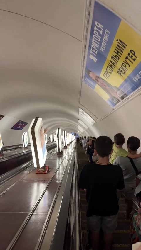 Passengers riding down a long escalator during rush hour in Kyiv metro Stock Footage 340324535