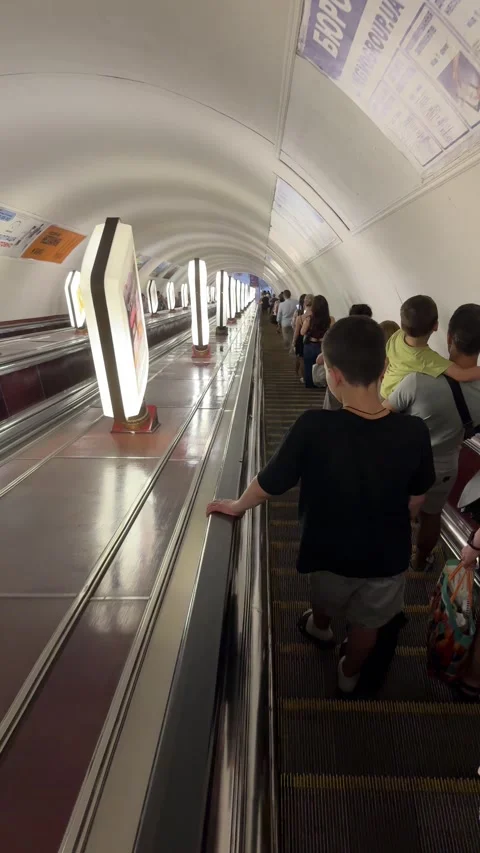 Passengers riding down a long escalator during rush hour in Kyiv metro Stock Footage 340324537