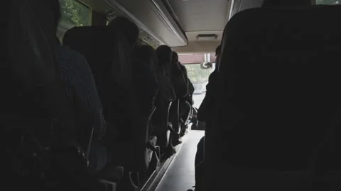 Passengers seated inside bus during daytime journey. View from aisle shows Stock Footage 278938913