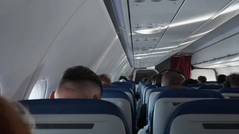 Passengers sit in seats inside commercial airplane cabin during daytime flight Stock Footage 343982959