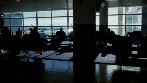 Passengers sit in a waiting airplane flight. People walk by, see the silhouettes Stock Footage 69270669