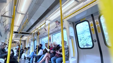 Passengers sitting and standing inside a London Underground District Line train Vidéo 327618917