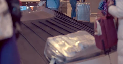 Passengers stand at the luggage carousel and wait for their belongings  Stock Footage 119602596
