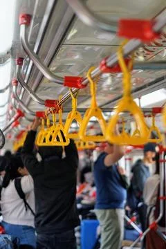 Passengers stand while holding yellow handrails in a crowded commuter electric Stock Photos