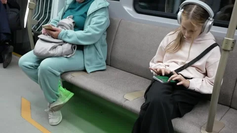 Passengers using smartphone at moving metro train. Teenage girl in headphones pl Stock Footage 295593657