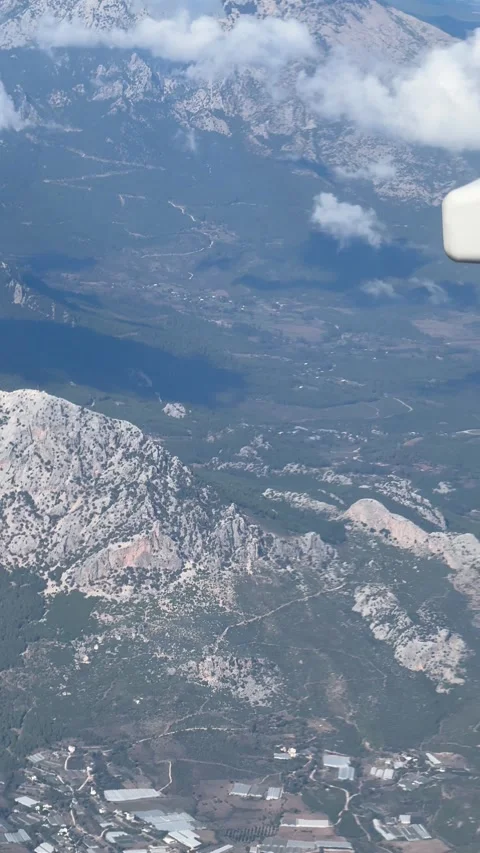 Passengers view from airplane window flying high above forest-covered mountai Stock Footage 321764069