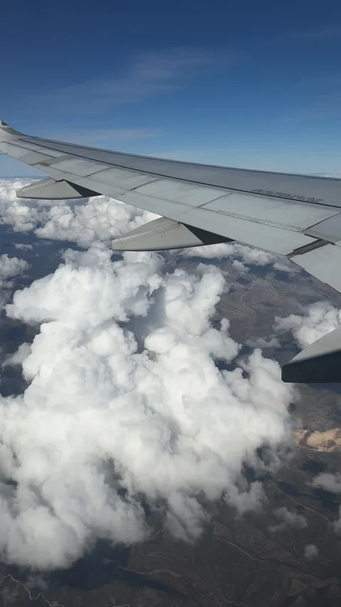 Passengers view from airplane window soaring above clouds and majestic mounta 動画素材 325649304