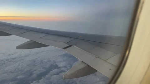 Passengers view from airplane window, wing visible against a stunning sunset  스톡 동영상 321764224
