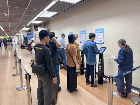 Passengers waiting and completing digital arrival declarations at automated Stock Photos