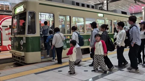 Passengers waiting in line to board a Hiroshima Electric Railway streetcar Video stock 337288599