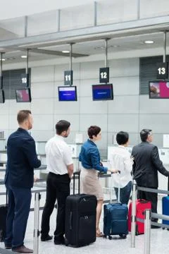 Passengers waiting in queue at a check-in counter with luggage 스톡 사진