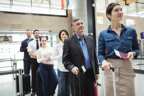 Passengers waiting in queue at a check-in counter with luggage Foto stock