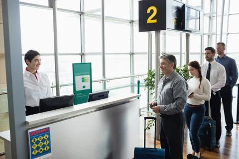 Passengers waiting in queue at check-in counter Stock Photos