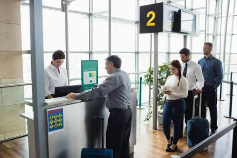 Passengers waiting in queue at check-in counter Stock Photos