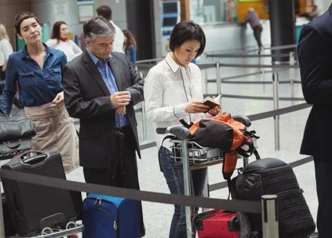 Passengers waiting in queue at a check-in counter with luggage Stock Photos
