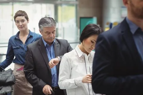 Passengers waiting in queue at a check-in counter with luggage Stock Photos