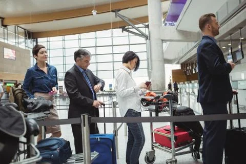 Passengers waiting in queue at a check-in counter with luggage 스톡 사진