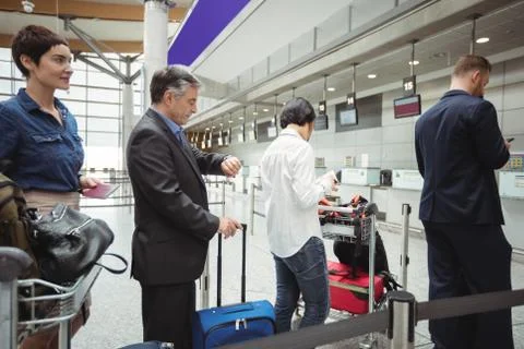 Passengers waiting in queue at a check-in counter with luggage 스톡 사진