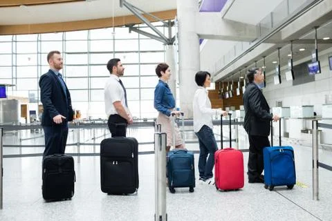 Passengers waiting in queue at a check-in counter with luggage Stock Photos