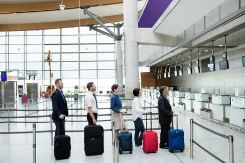 Passengers waiting in queue at a check-in counter with luggage Stock Photos