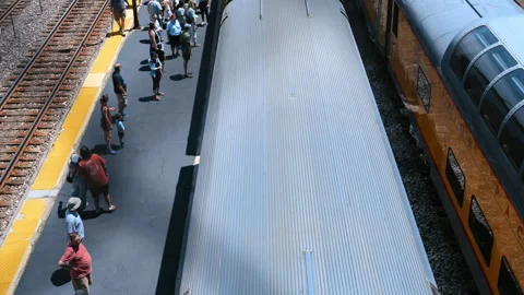 Passengers waiting at a railway station platform as a passenger train arrives Stock Footage 338319498