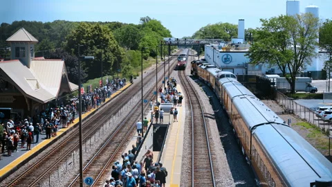 Passengers waiting at a railway station platform as a passenger train arrives Stock Footage 340383082