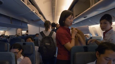 Passengers Walk Down the Aisle, Put Things Up, Sit in Chairs Inside the Plane Stock Footage 122989908