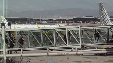 Passengers walk through the boarding bridge at El Prat Airport in Barcelona Stock Footage 324279251