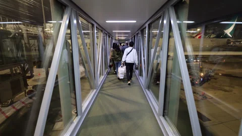 Passengers walking down the jet bridge to board a plane at night Vídeo Stock 341110578