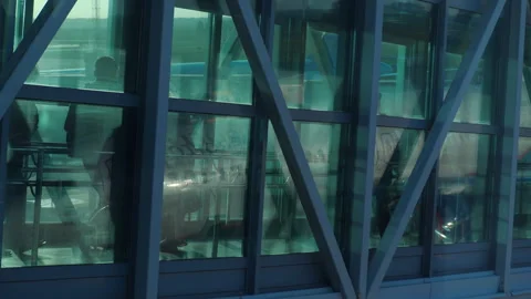 Passengers walking through glass jet bridge to airplane at airport Stock Footage 346351983