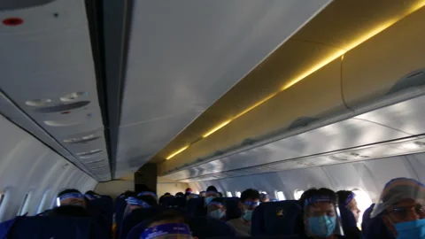 Passengers wearing face shields and mask inside an airplane Stock Footage 281317424