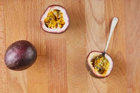 Passiflora is cut into two halves with a spoon inside and a whole on a wooden Stock Photos