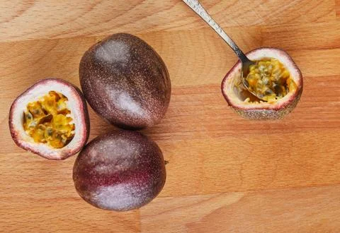 Passiflora is cut into two halves with a spoon inside and two whole on a wood Stock Photos